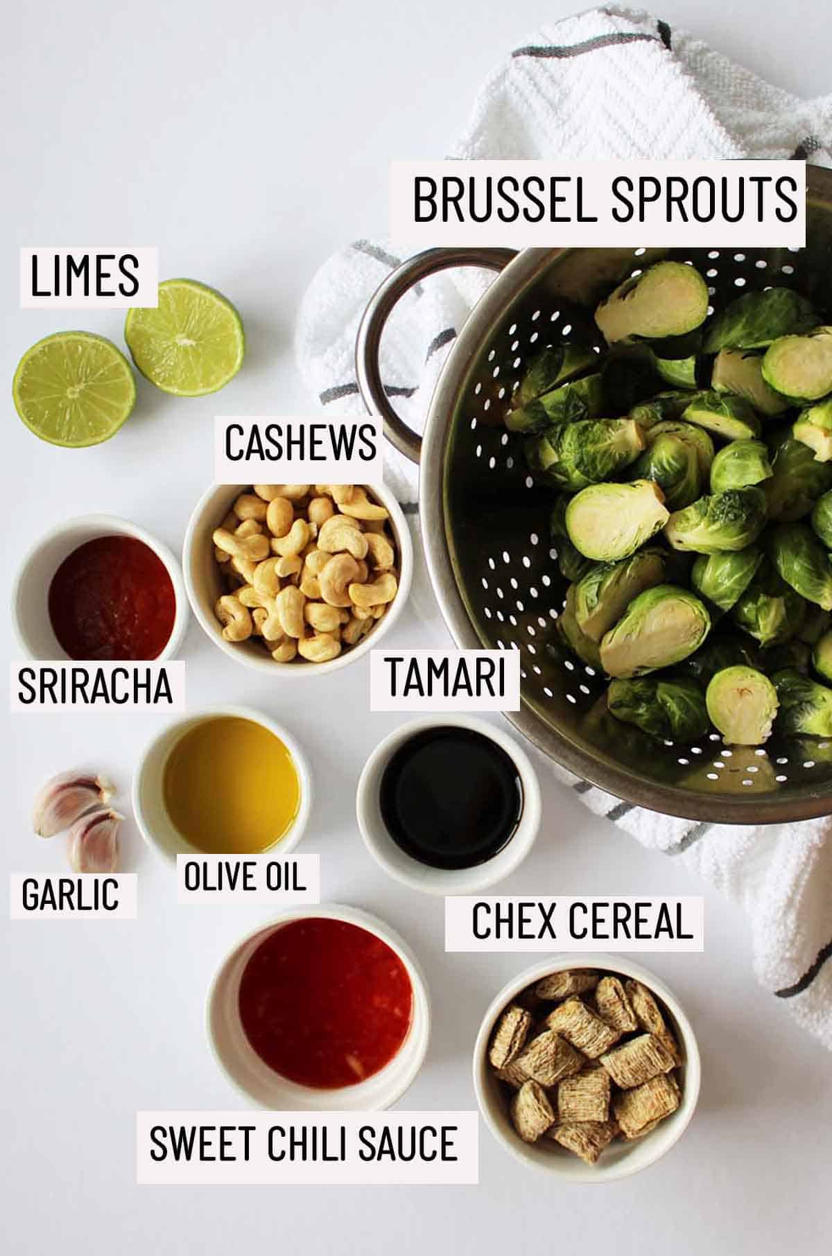 Birds eye view of portioned ingredients to make sweet and spicy brussel sprouts including brussel sprouts, lime, cashews, sriracha, garlic, olive oil, tamari, sweet chili sauce and chex cereal.