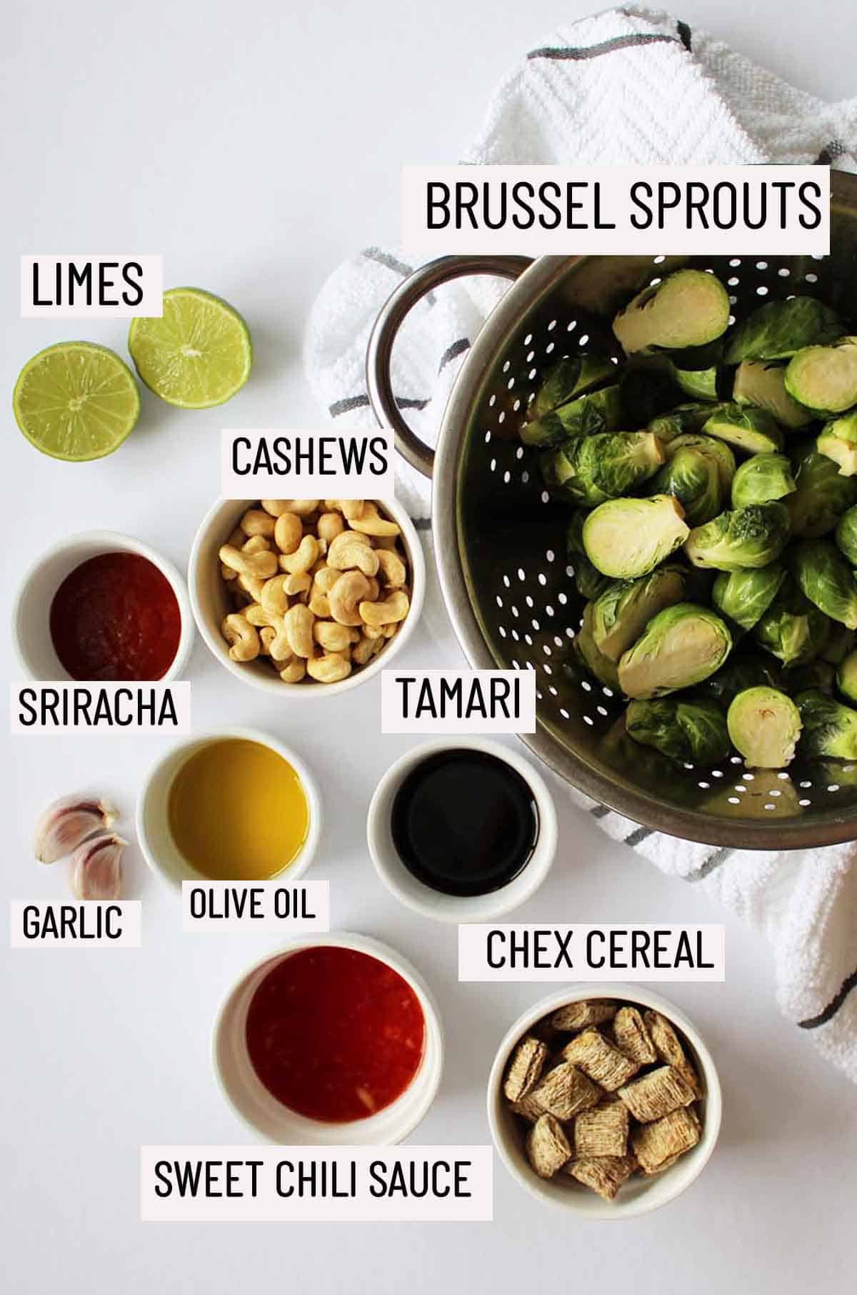 Birds eye view of portioned ingredients to make sweet and spicy brussel sprouts including brussel sprouts, lime, cashews, sriracha, garlic, olive oil, tamari, sweet chili sauce and chex cereal. 