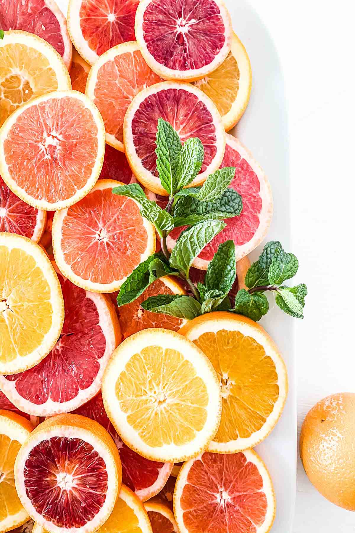 Several slices of citrus fruit on a plater including blood orange, orange, and grapefruit. 