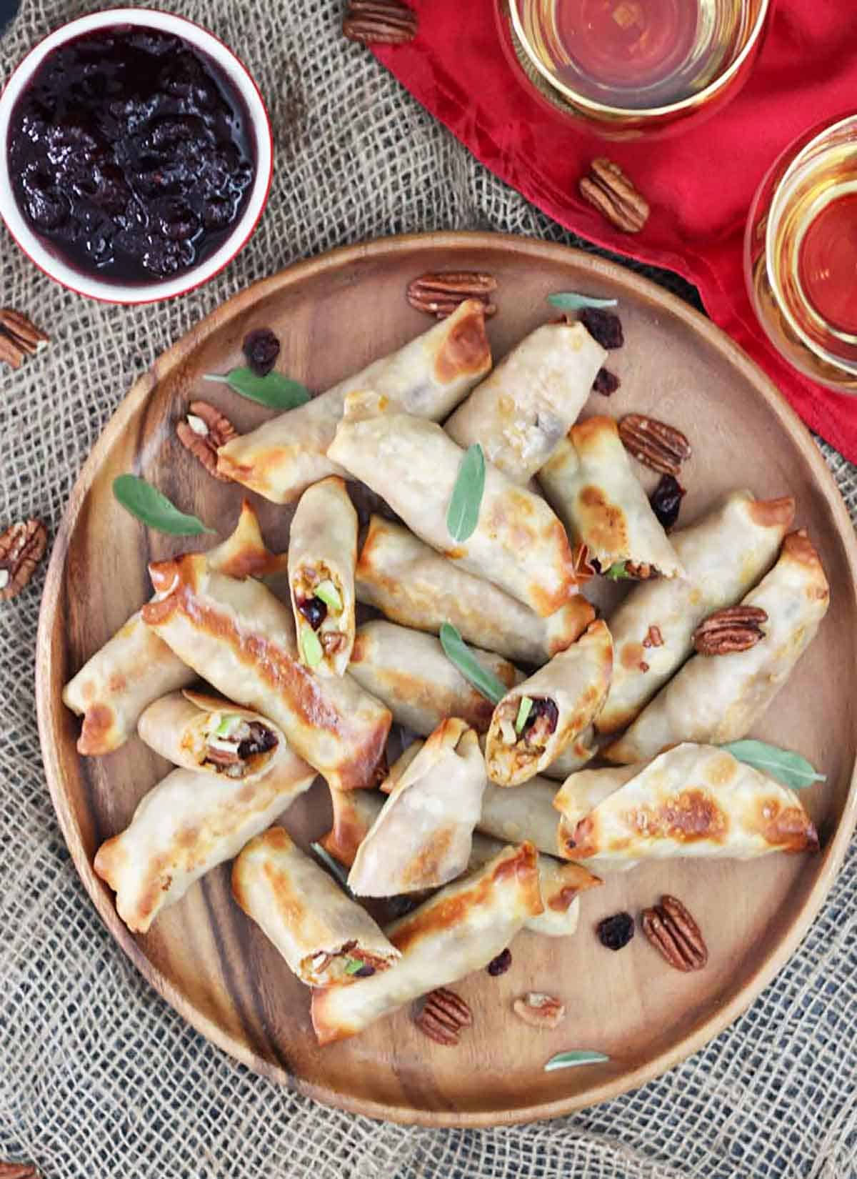 Birds eye view of several risotto bring rolls on a wooden plate garnished with fresh sage leaves and pecans. 