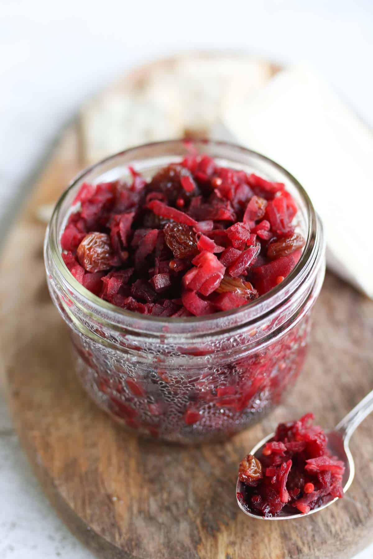 Close up of apple chutney in a jar with a spoon on the side. 