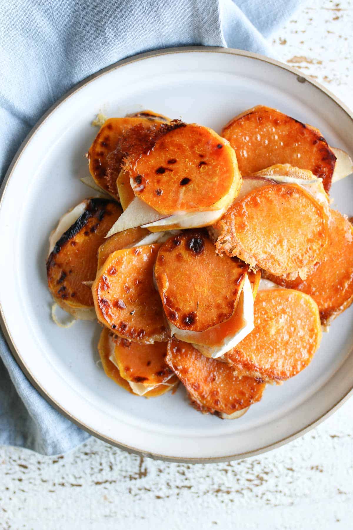 Sweet potatoes bites stacked in a pile on a white plate.