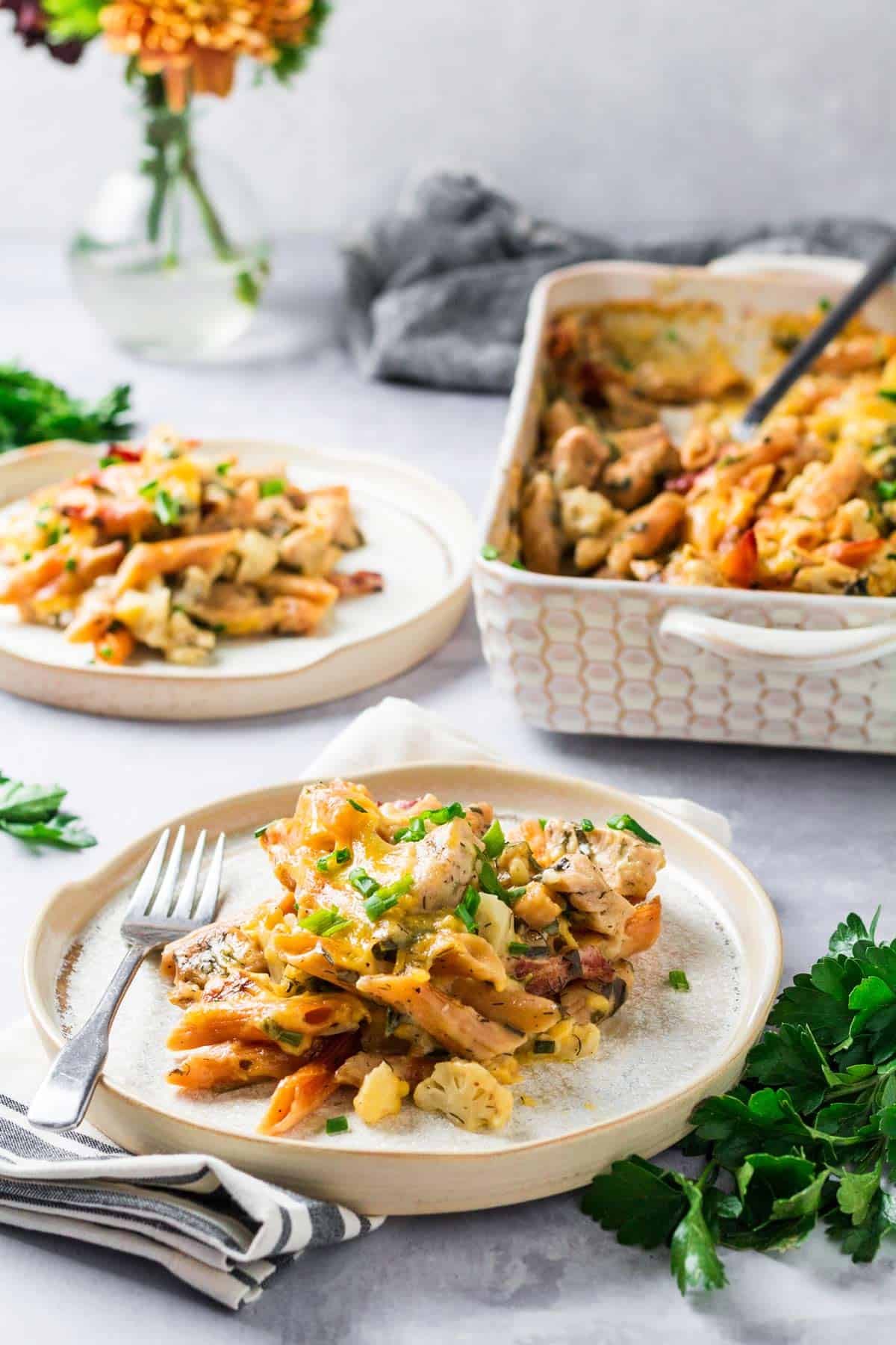 Plate with chicken bacon ranch pasta on it with a fork with the casserole dish in the background.