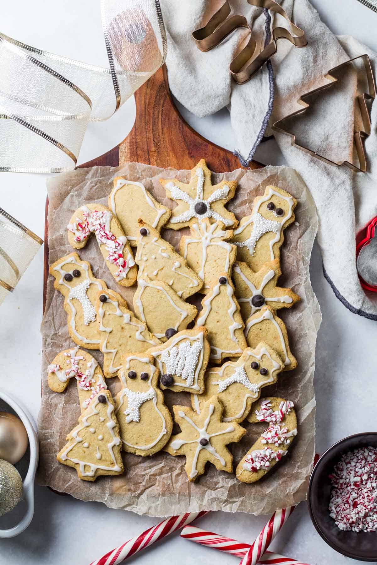 Birds eye view image of gluten free Christmas cookies on parchment paper surrounding by candy canes and Christmas ornaments. 