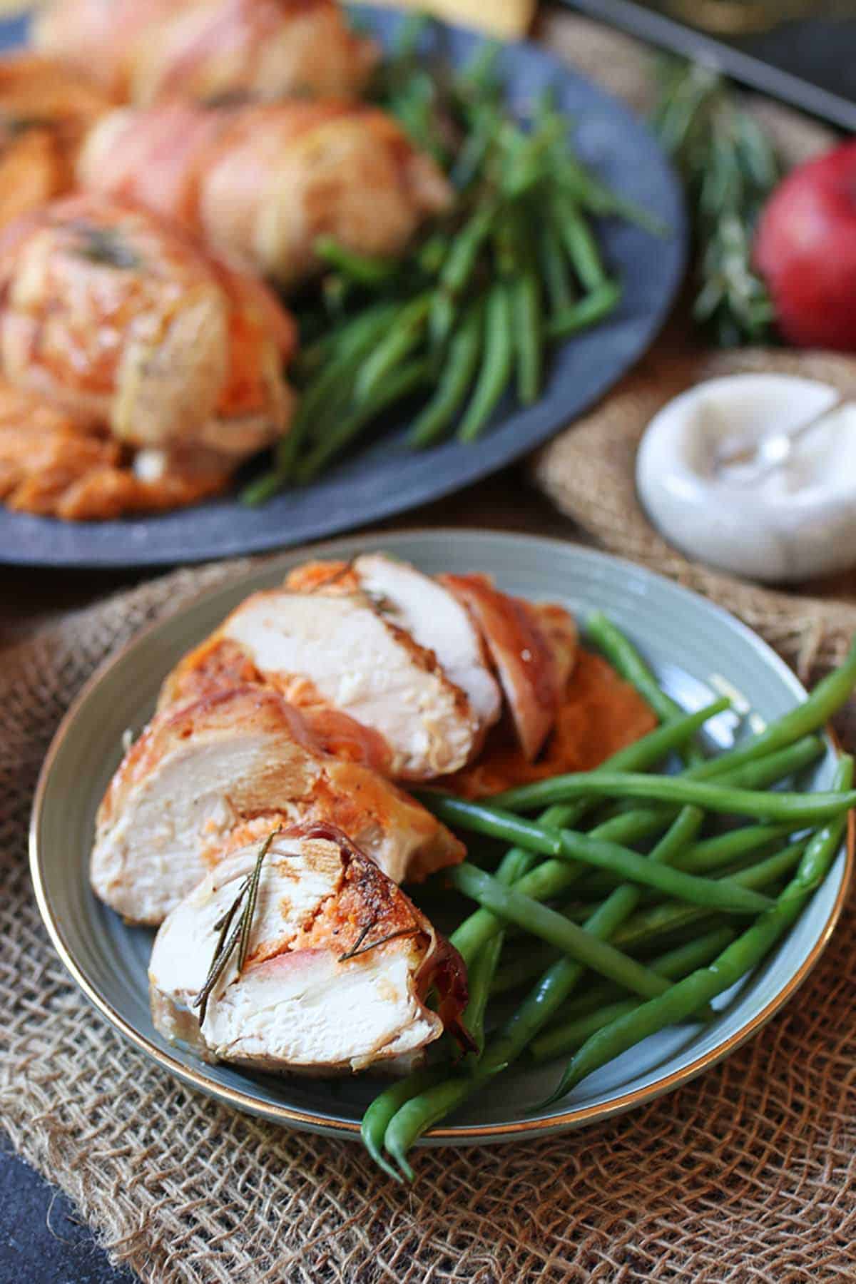 Complete holiday recipe cut in four pieces on a blue plate with green beans on the side. 