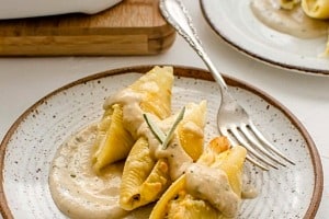 Plate with three stuffed shells with sauce drizzled overtop.