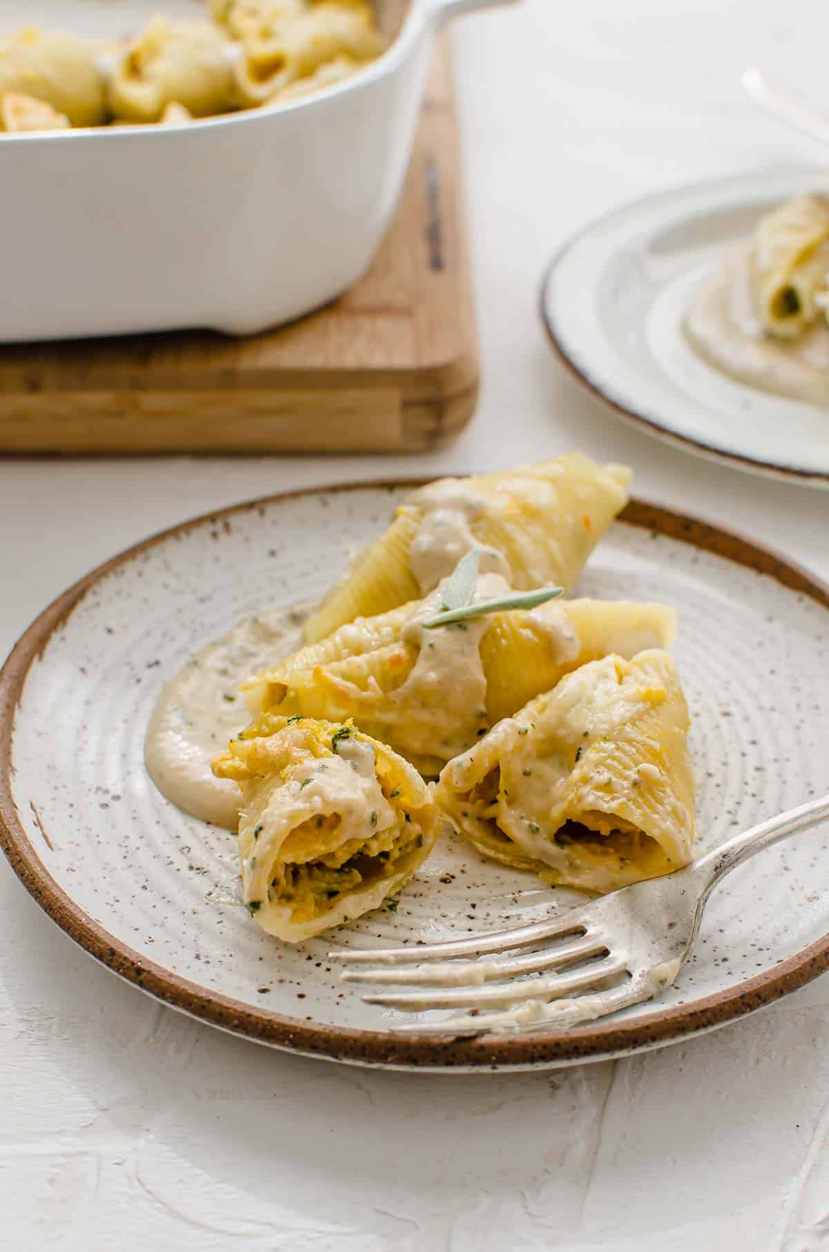 Butternut squash stuffed pasta shells on a plate cut in half.