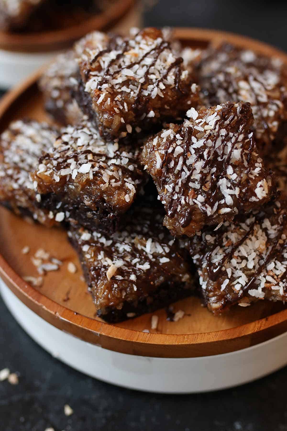 Close up of samoa brownies stacked on a wooden plate.