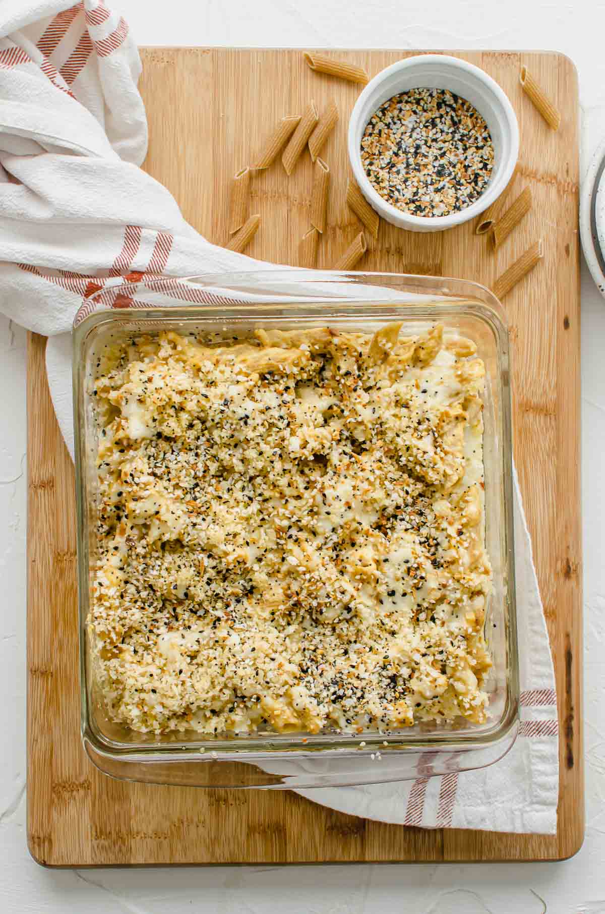 A baking dish filled with baked vegan mac and cheese on a serving board.