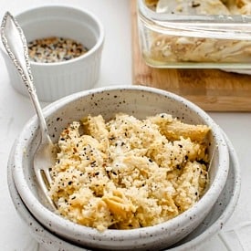 A bowl of baked vegan mac and cheese in a bowl with a fork inside of it.