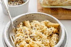 A bowl of baked vegan mac and cheese in a bowl with a fork inside of it.