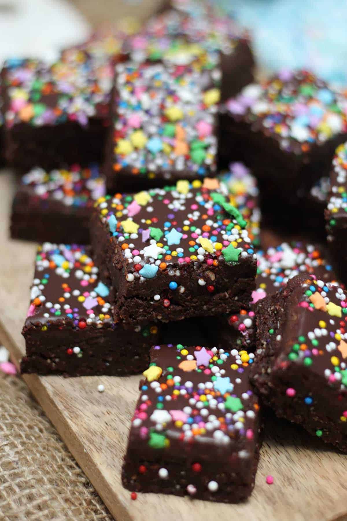 Several no bake brownie squares on a wooden cutting board. 