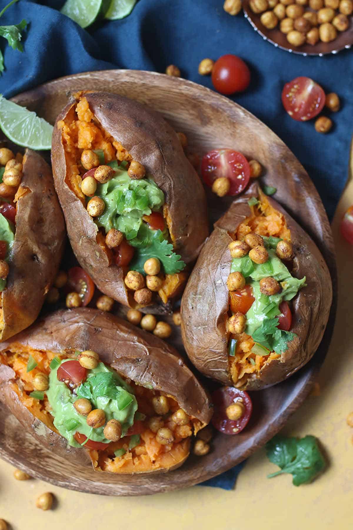 Birds eye view of four avocado stuffed sweet potatoes with guacamole and crispy chickpeas and garnished with cilantro. 