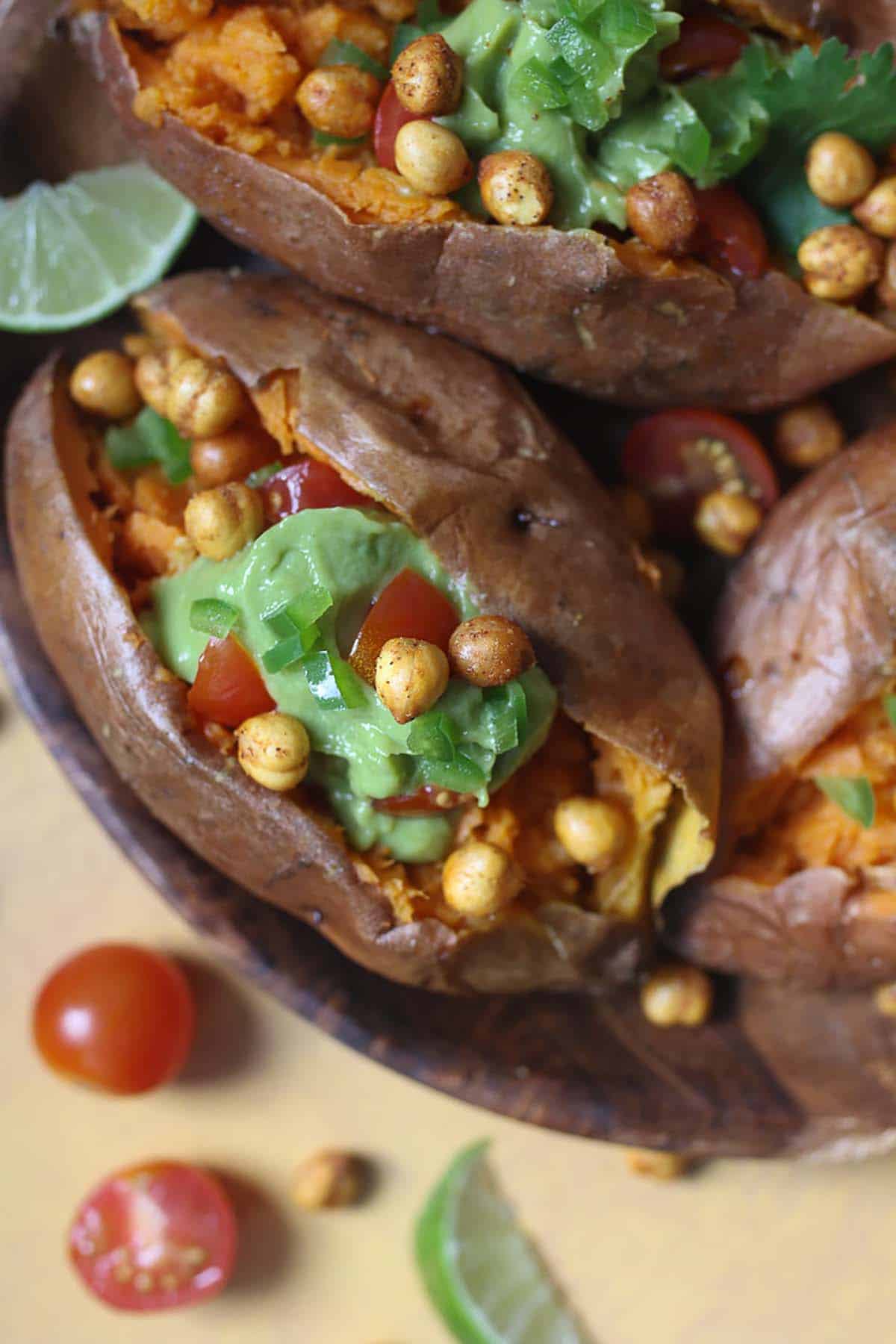 Close up of avocado stuffed sweet potato garnished with cilantro and tomato. 