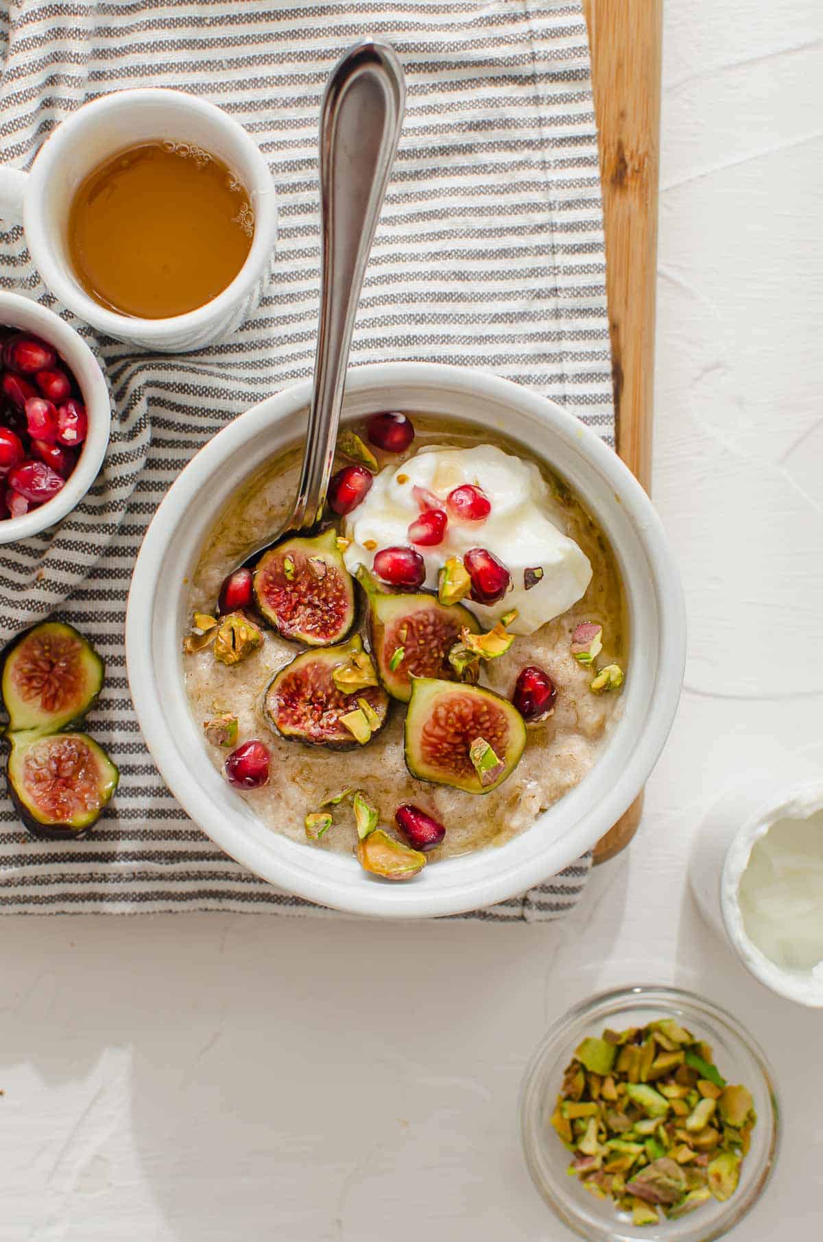 Birds eye view of Mediterranean oatmeal bowl topped with figs, yogurt, pistachios, and pomegranate. 
