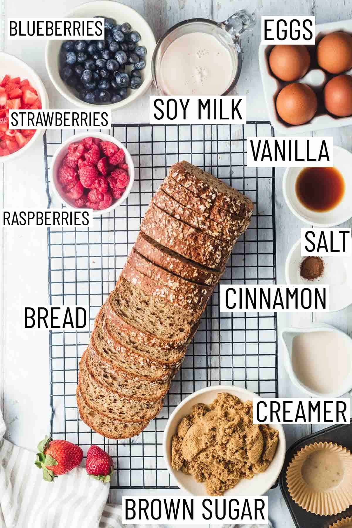 Overhead image of ingredients: soy milk, eggs, vanilla, salt, cinnamon, creamer, brown sugar, bread, berries.