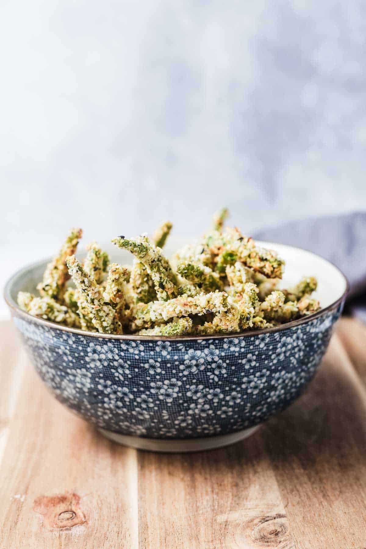 Several green bean fries in a blue floral bowl. 