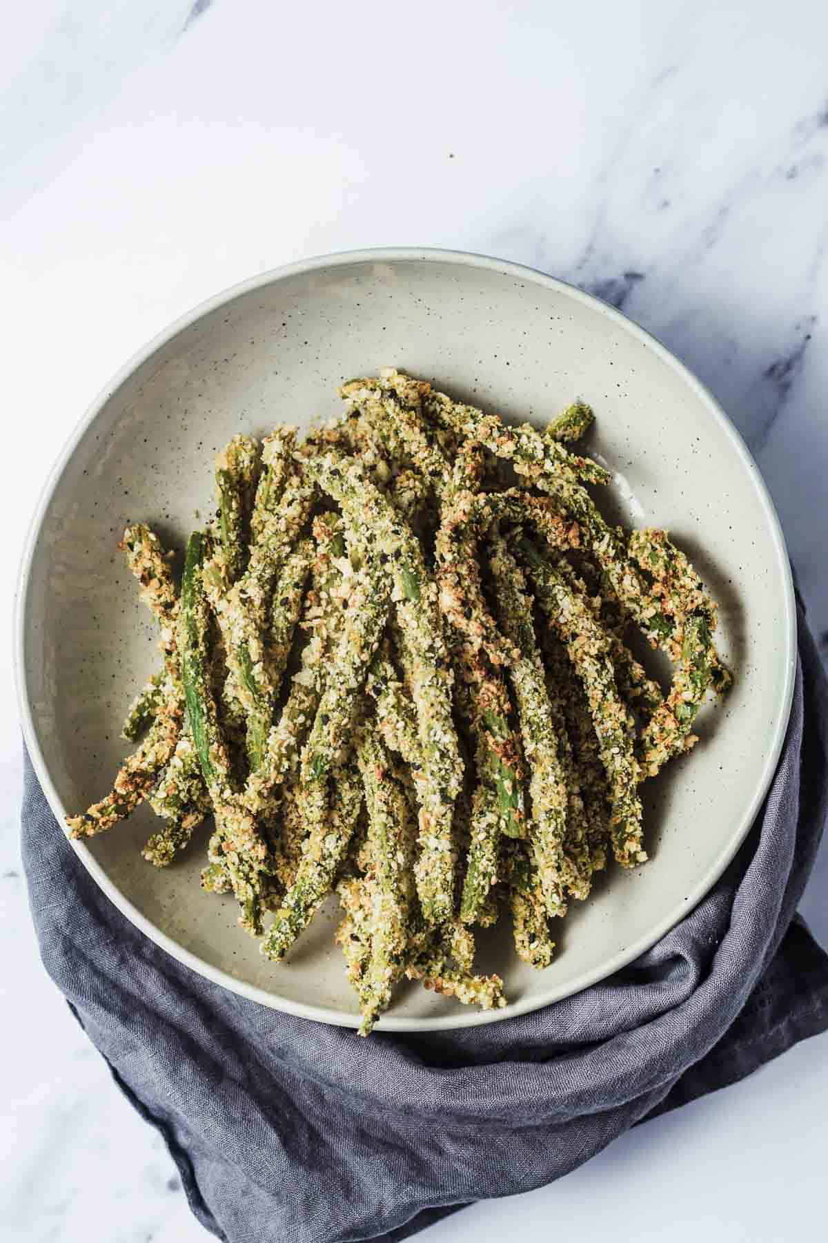 Birds eye view of green bean fries laying flat on a white plate. 