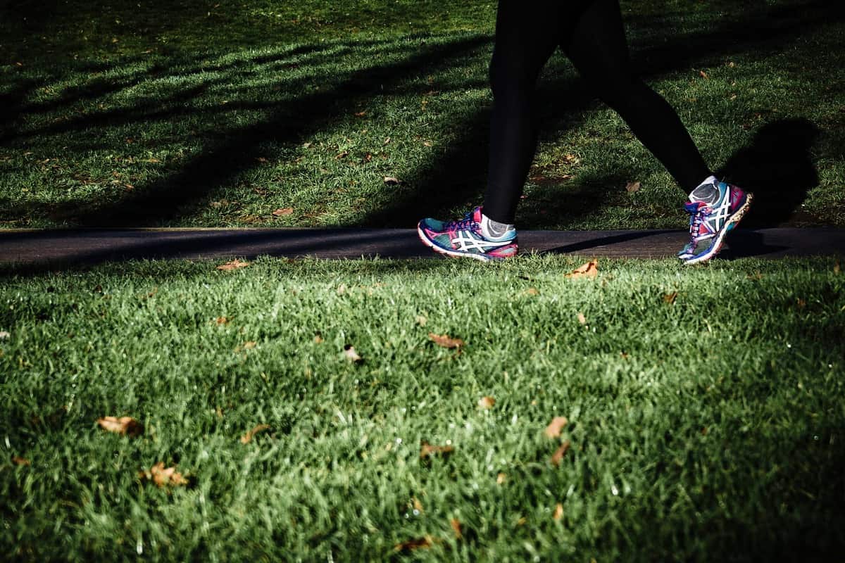 A person wearing colourful running shoes and walking outside to minimize weight gain on period.