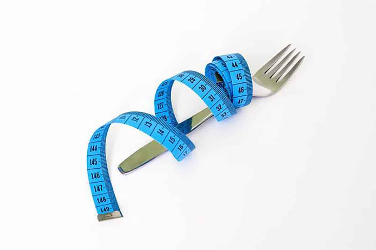 Measuring tape wrapped around a silver fork for weight loss.