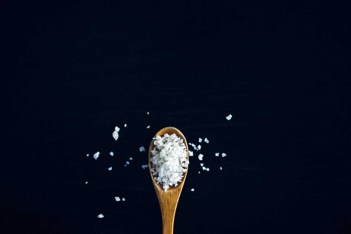 A wooden spoon with flakey salt. 