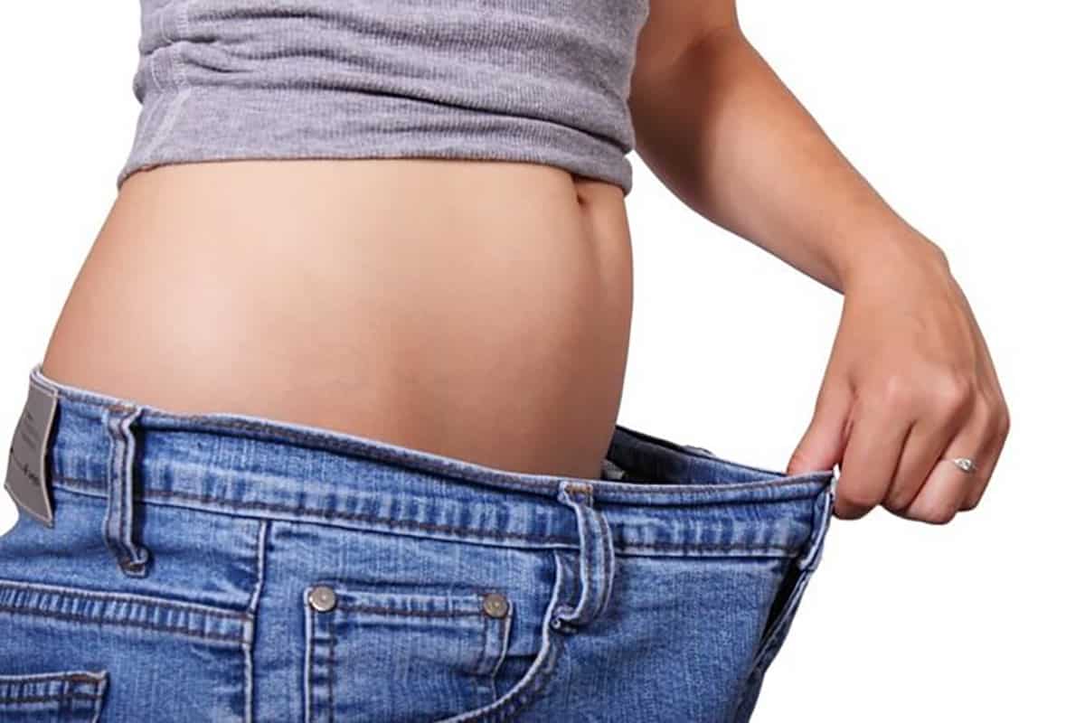 Woman wearing loose pants after losing weight from intermittent fasting.