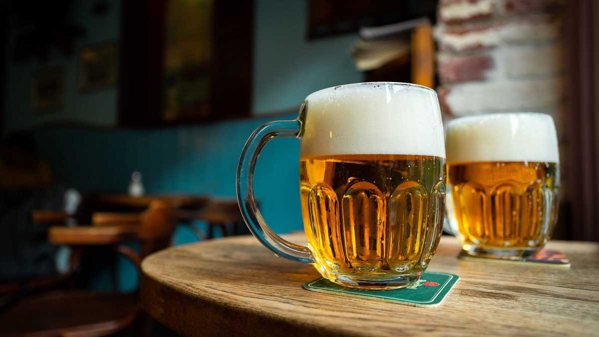 Two pitchers of beer on a wooden table. 