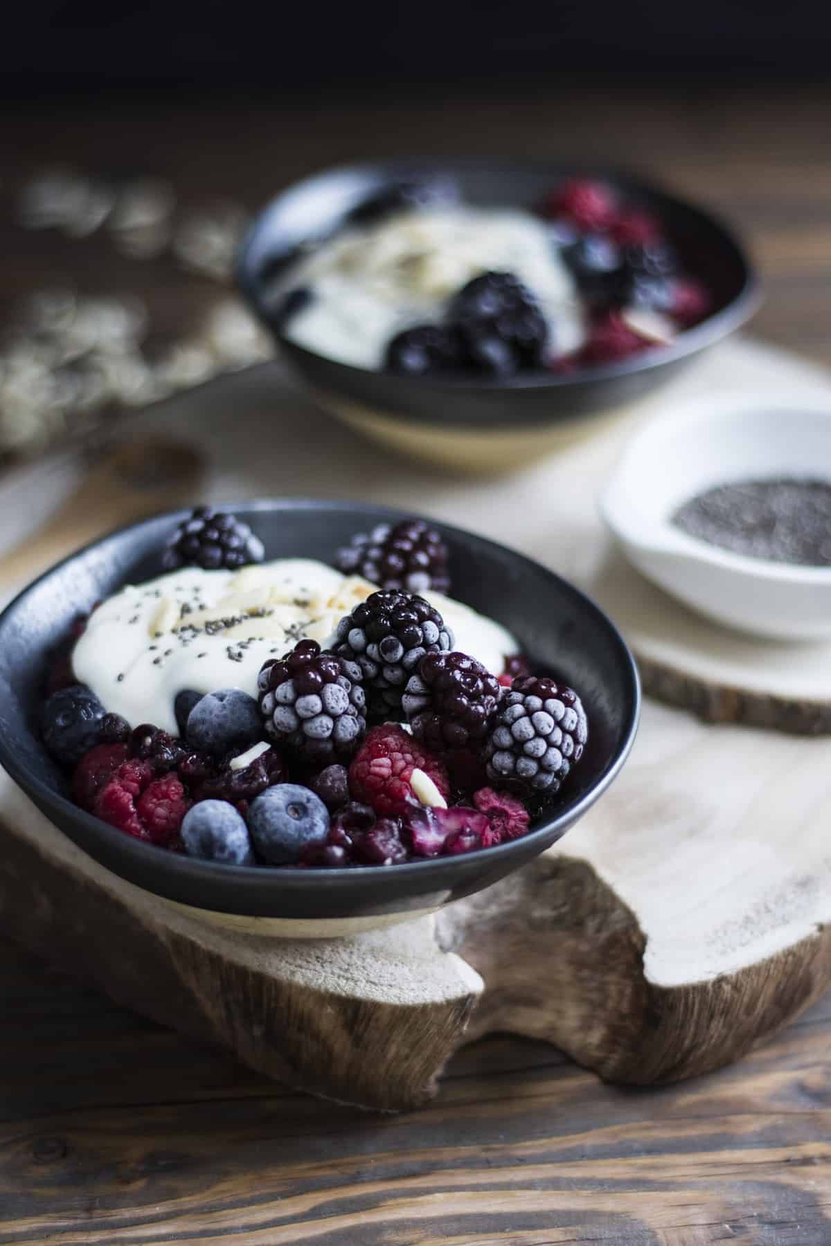 A bowl of yogurt topped with frozen berries. 