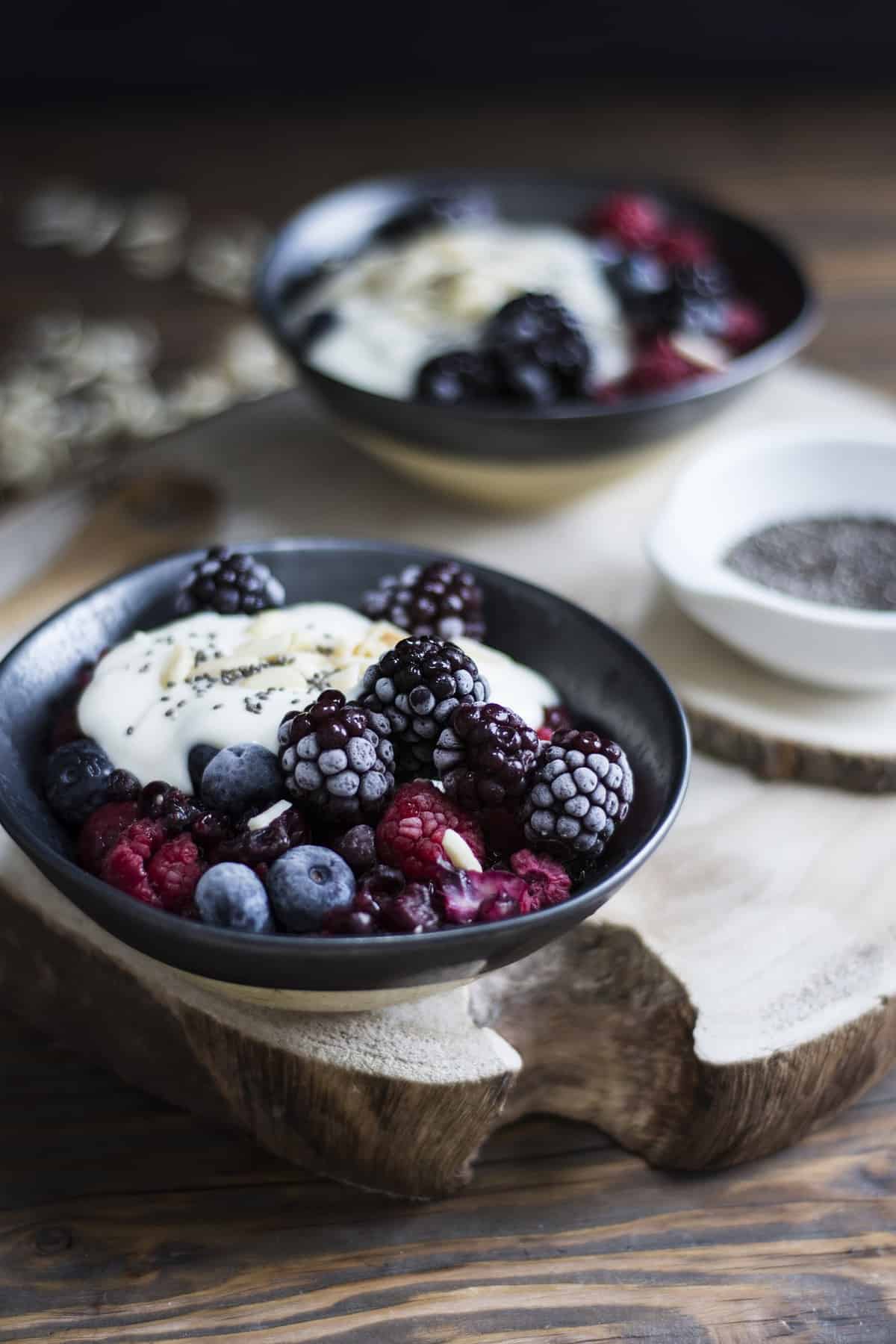 A bowl of yogurt topped with frozen berries.