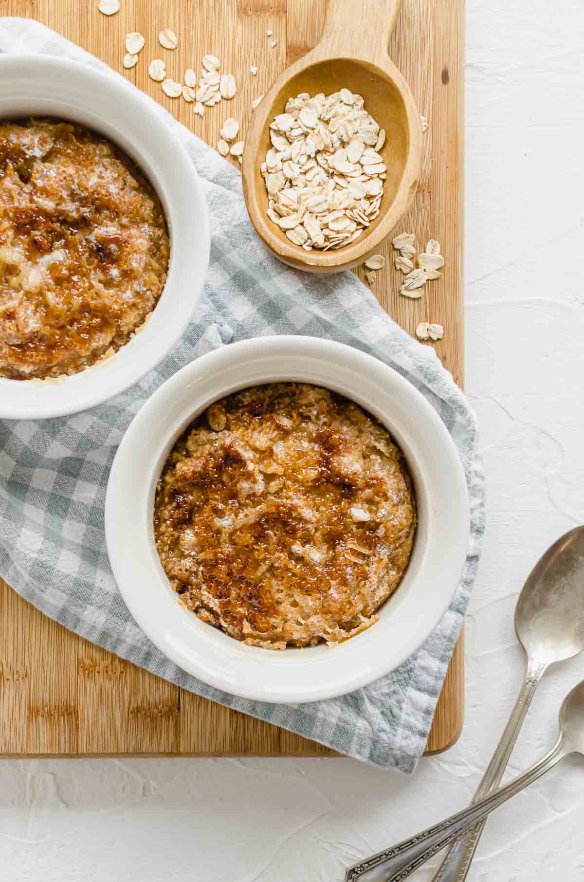 A birds eye view image of high protein oatmeal in a white bowl with a wooden spoon with oats, and a second portion in the background. 