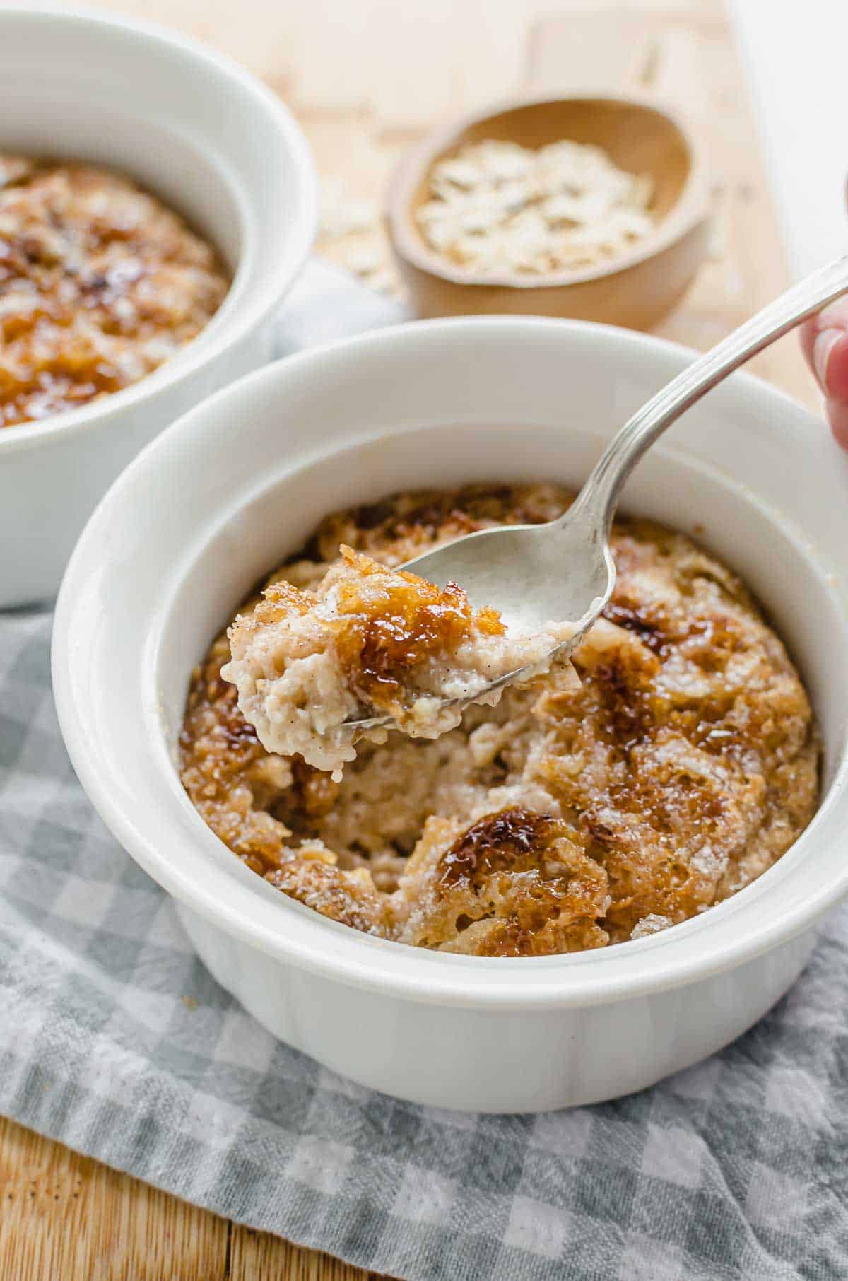 A spoon picking up a bite of high protein oatmeal from a white bowl. 