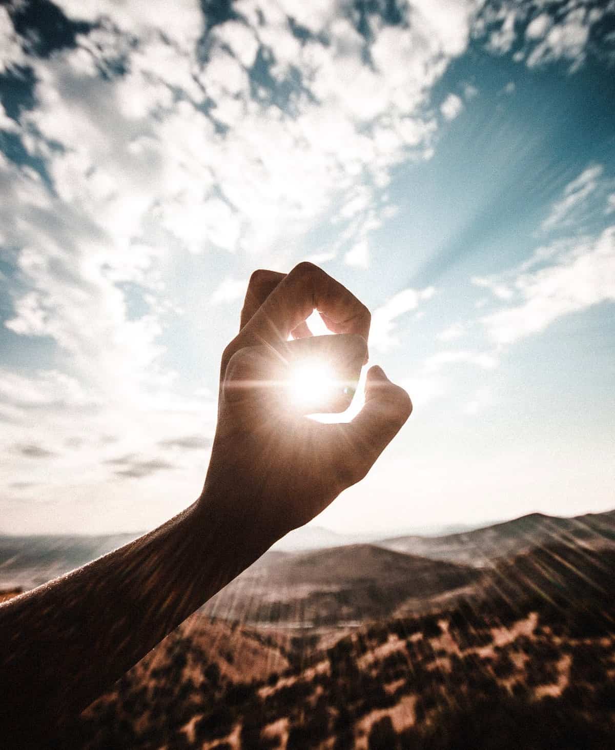 A person holding up their hand against the sun. 