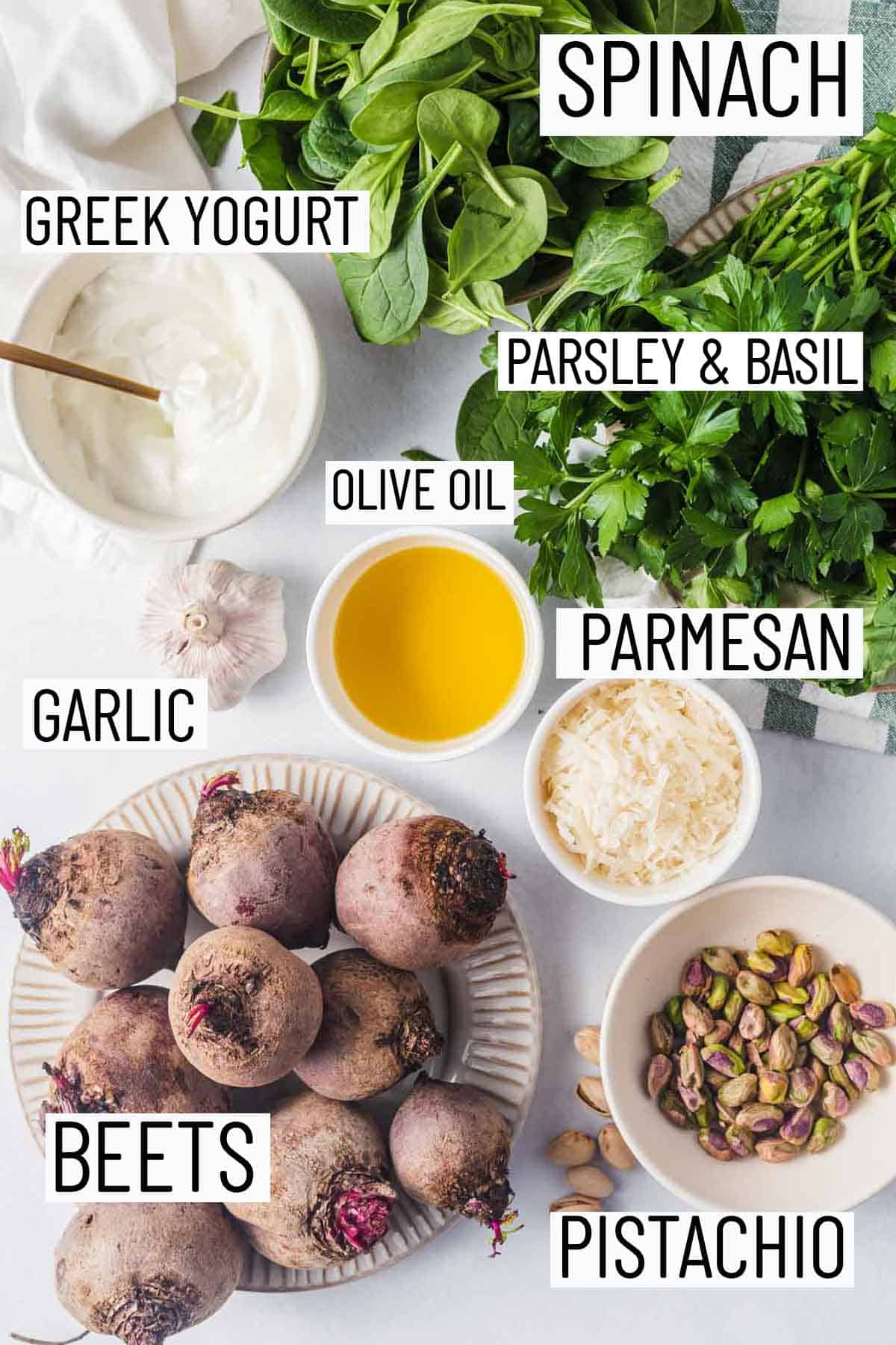 Flat lay images of portioned ingredients for recipe including beets, pistachio, parmesan, olive oil, garlic, parsley, basil, and spinach. 