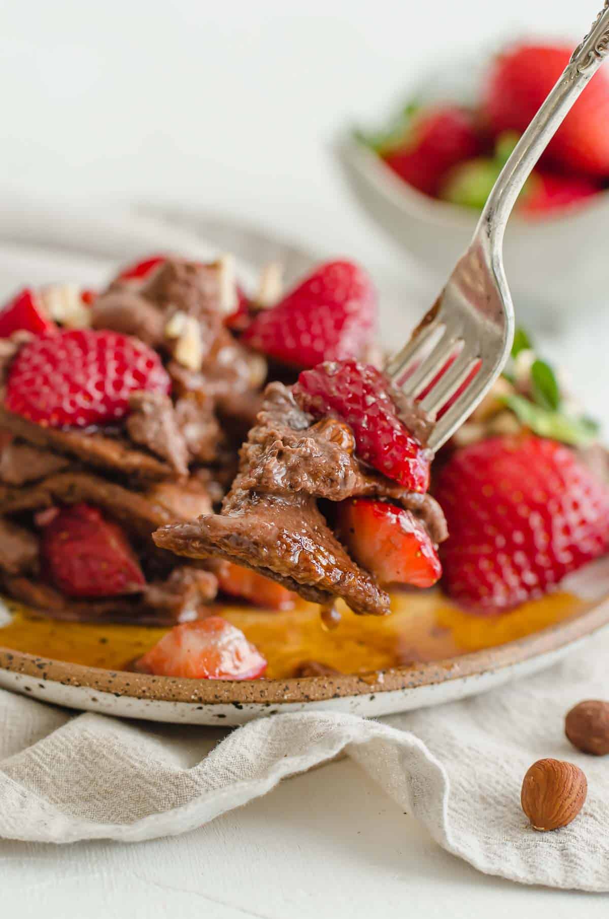 A fork with taking a bite of Nutella stuffed pancakes.