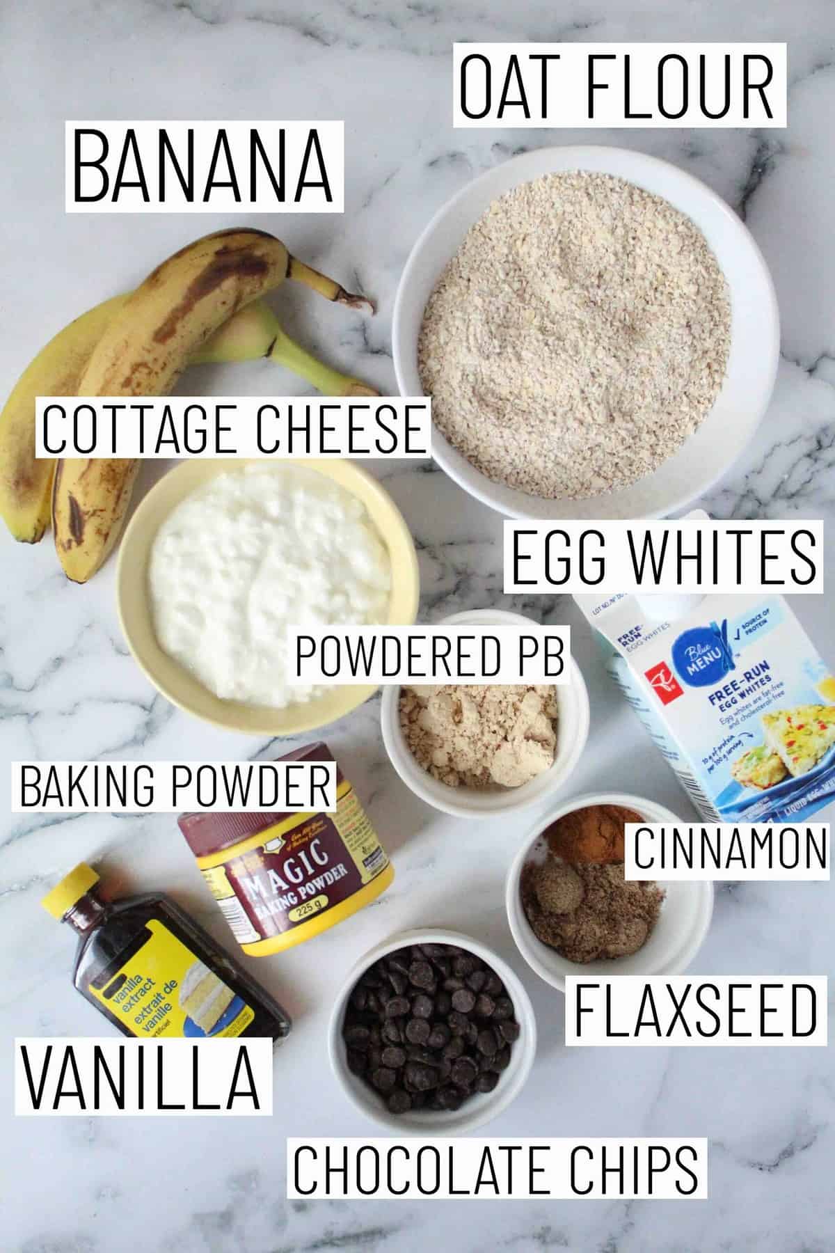 Flat lay image of portioned recipe ingredients including oat flour, bananas, cottage cheese, powdered peanut butter, egg whites, cinnamon, flaxseed, vanilla, chocolate chips, and baking powder. 