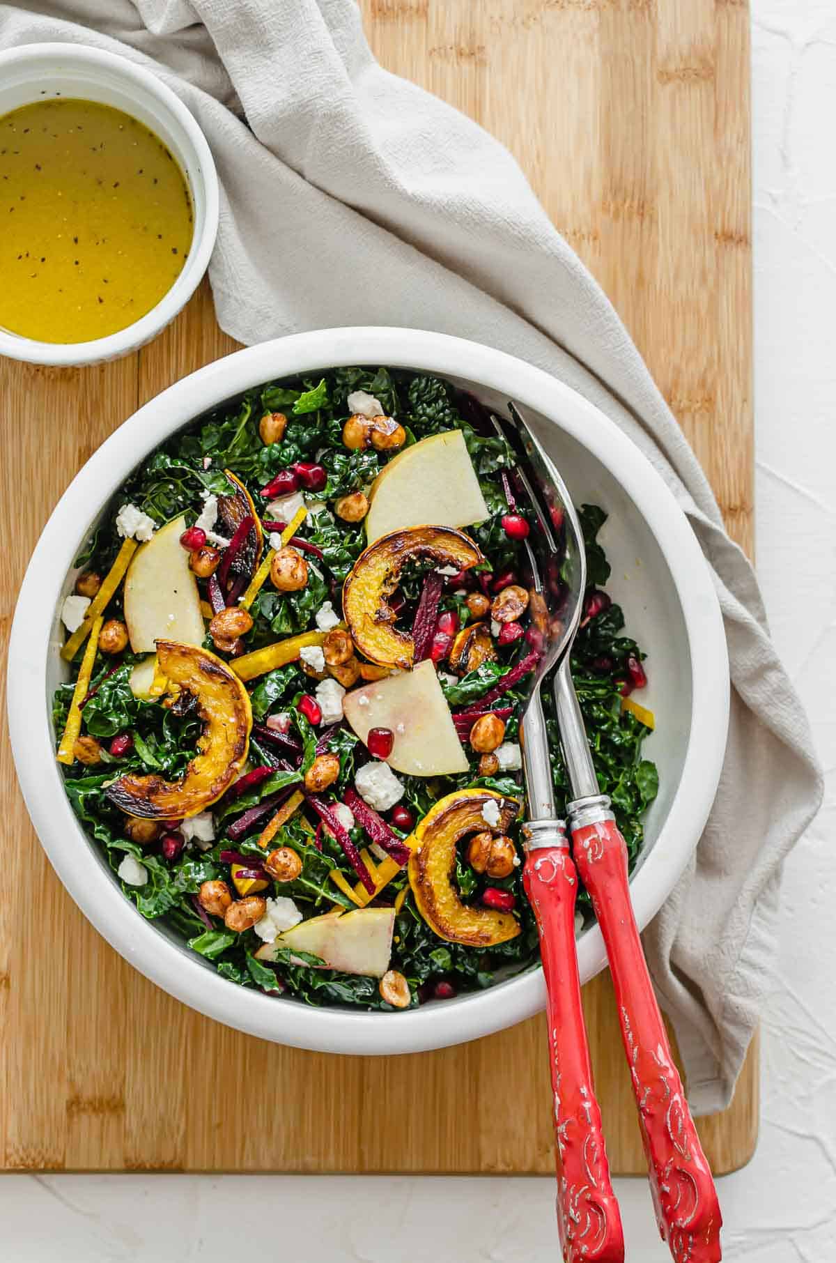 Birds eye view of salad recipe in a white serving bowl with serving spoons. 