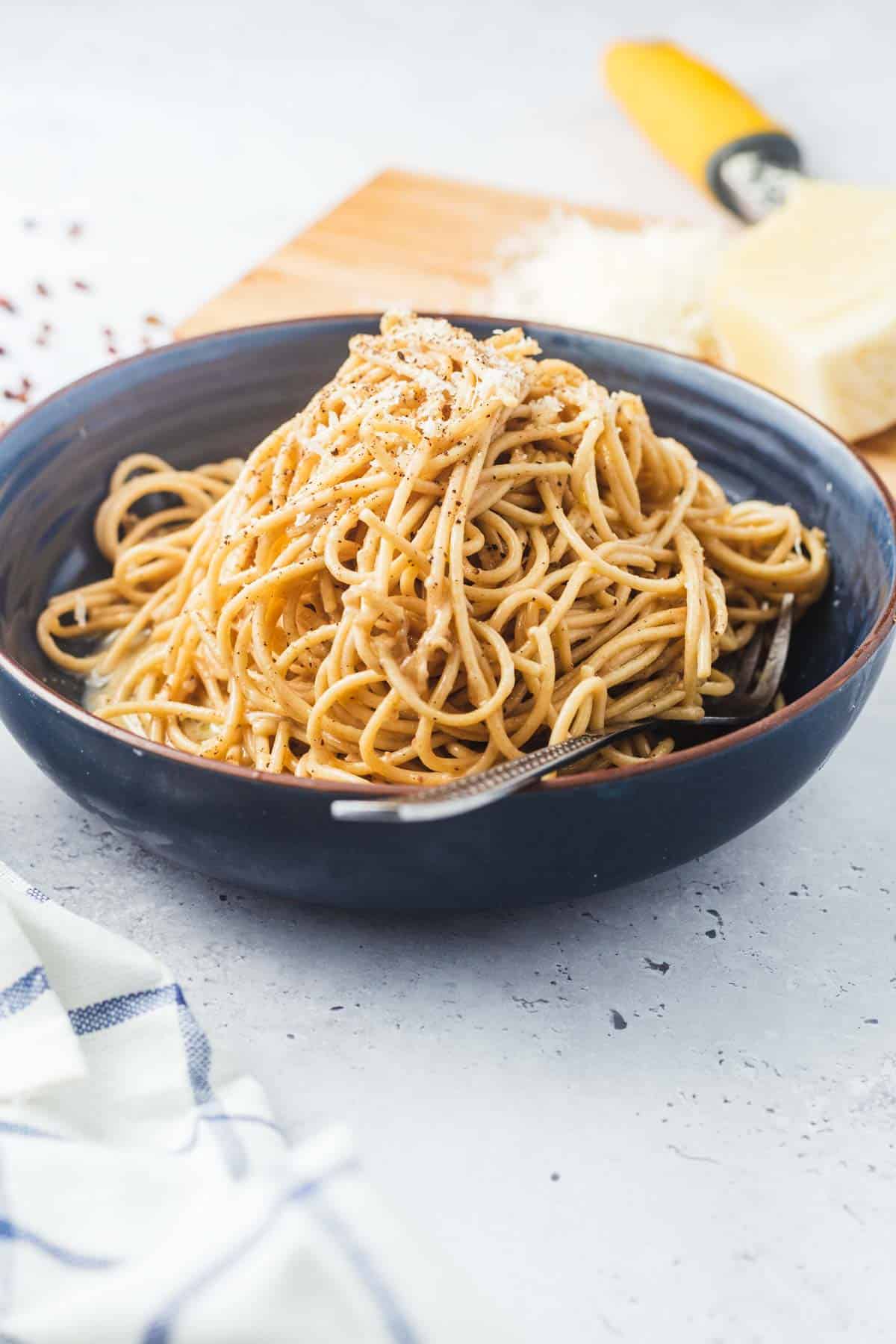 Szechuan Cacio e Pepe in a blue bowl topped with grated cheese. 