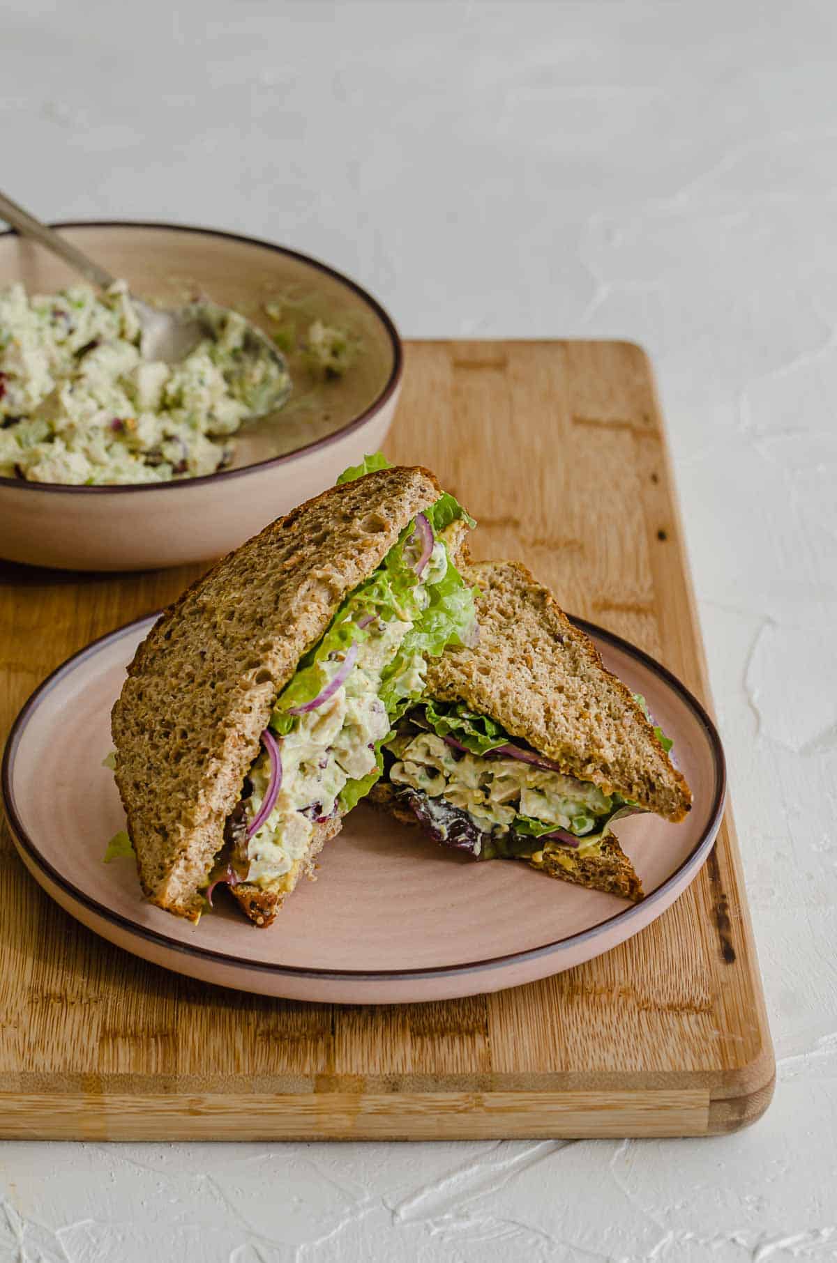 Close up of cranberry chicken salad in a sandwich on a pink plate.