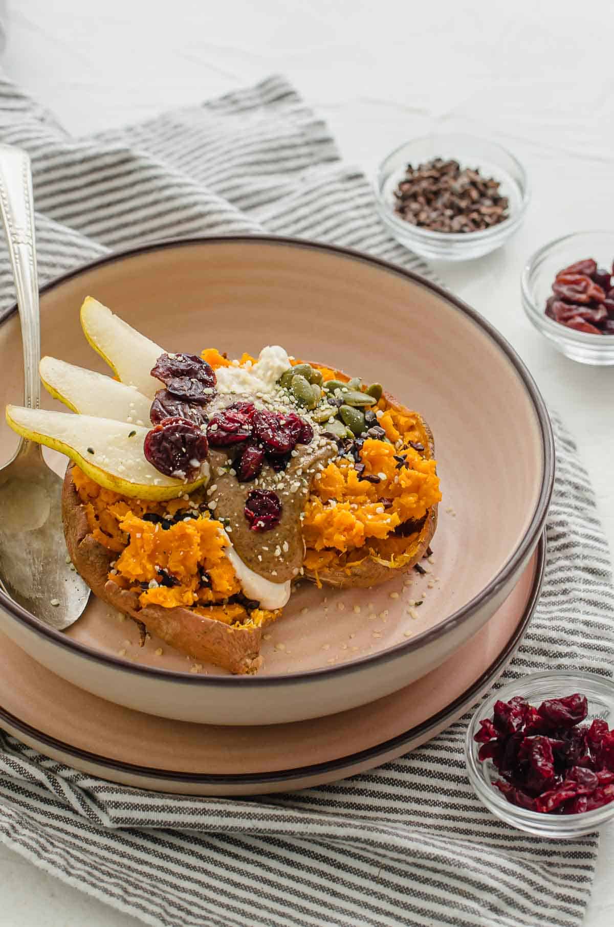 Close up of sweet potato breakfast bowl with toppings in a pink bowl. 