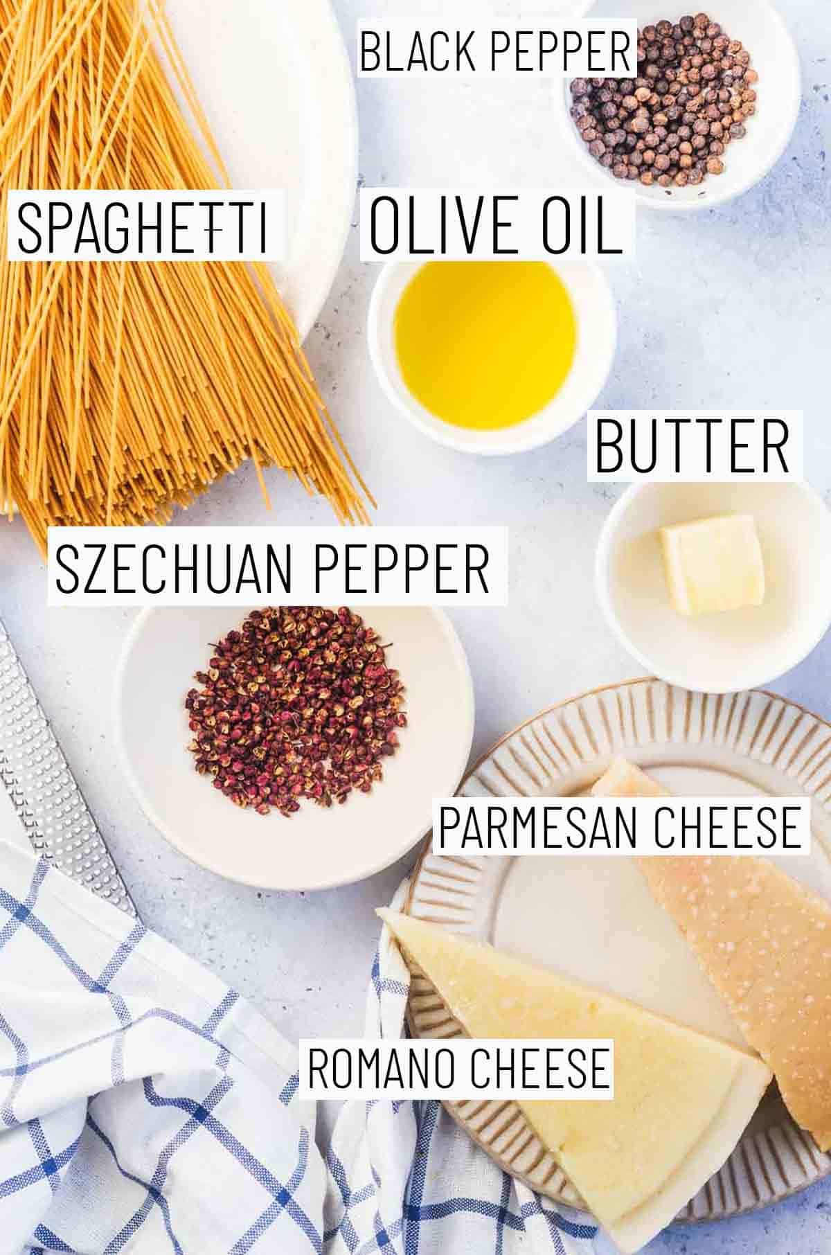 Flat lay image of recipe ingredients including black pepper, olive oil, butter, spaghetti, parmesan cheese, Romano cheese, and Szechuan pepper. 