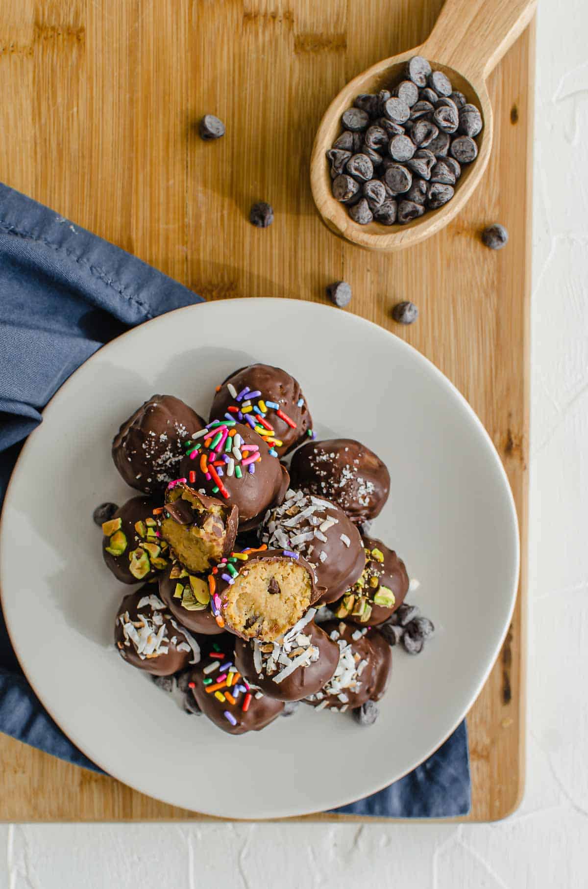 Birds eye view image of protein cookie dough bites on a white plate with chocolate chips in the background. 