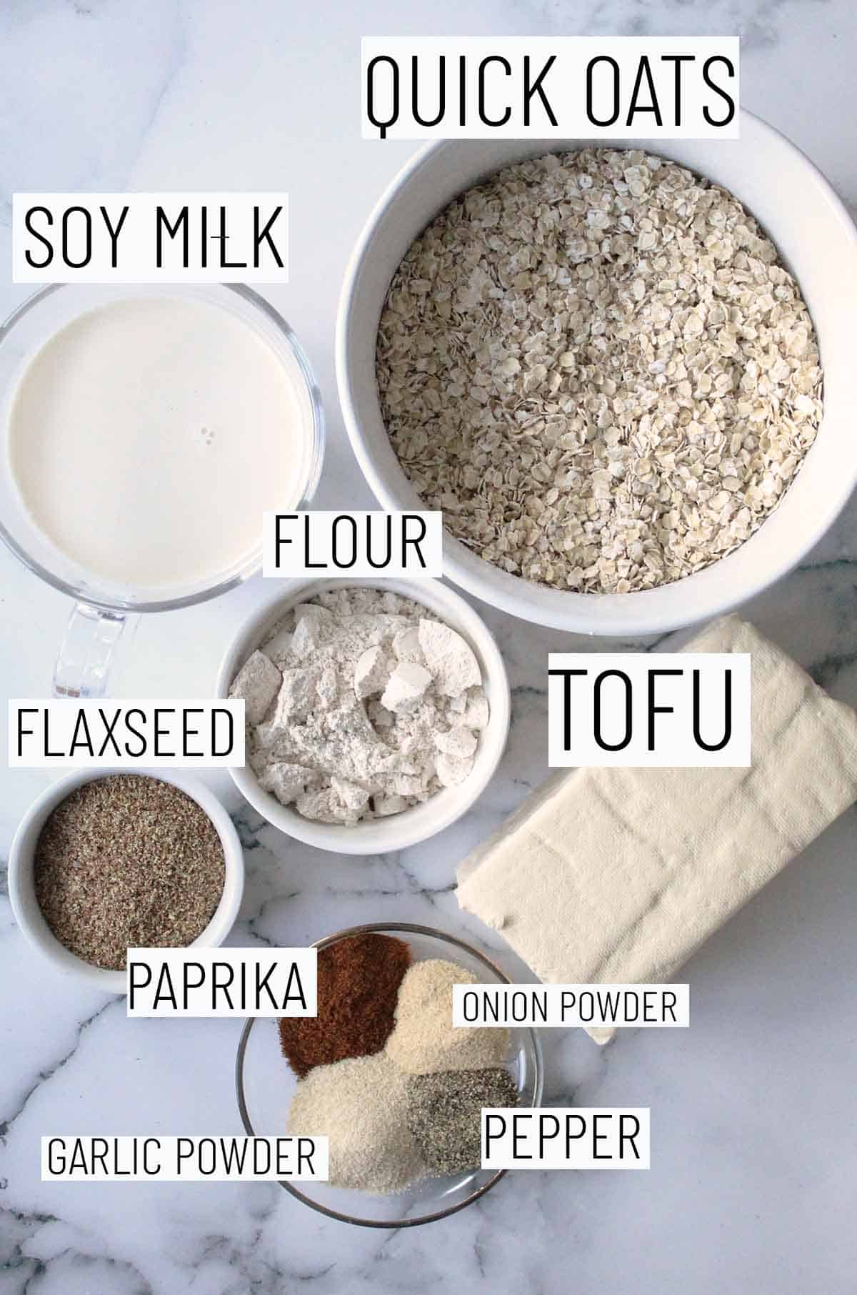 Flat lay image of recipe ingredients including oats, tofu, flour, soy milk, flaxseed, paprika, onion powder, garlic powder, and pepper.