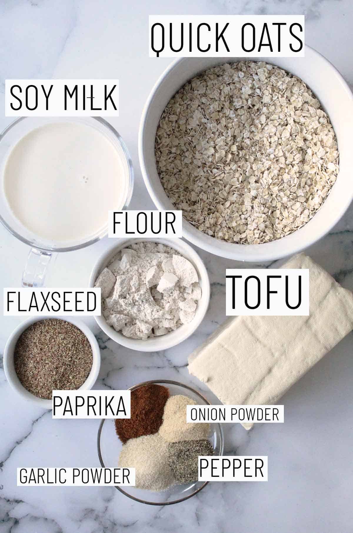 Flat lay image of recipe ingredients including oats, tofu, flour, soy milk, flaxseed, paprika, onion powder, garlic powder, and pepper. 