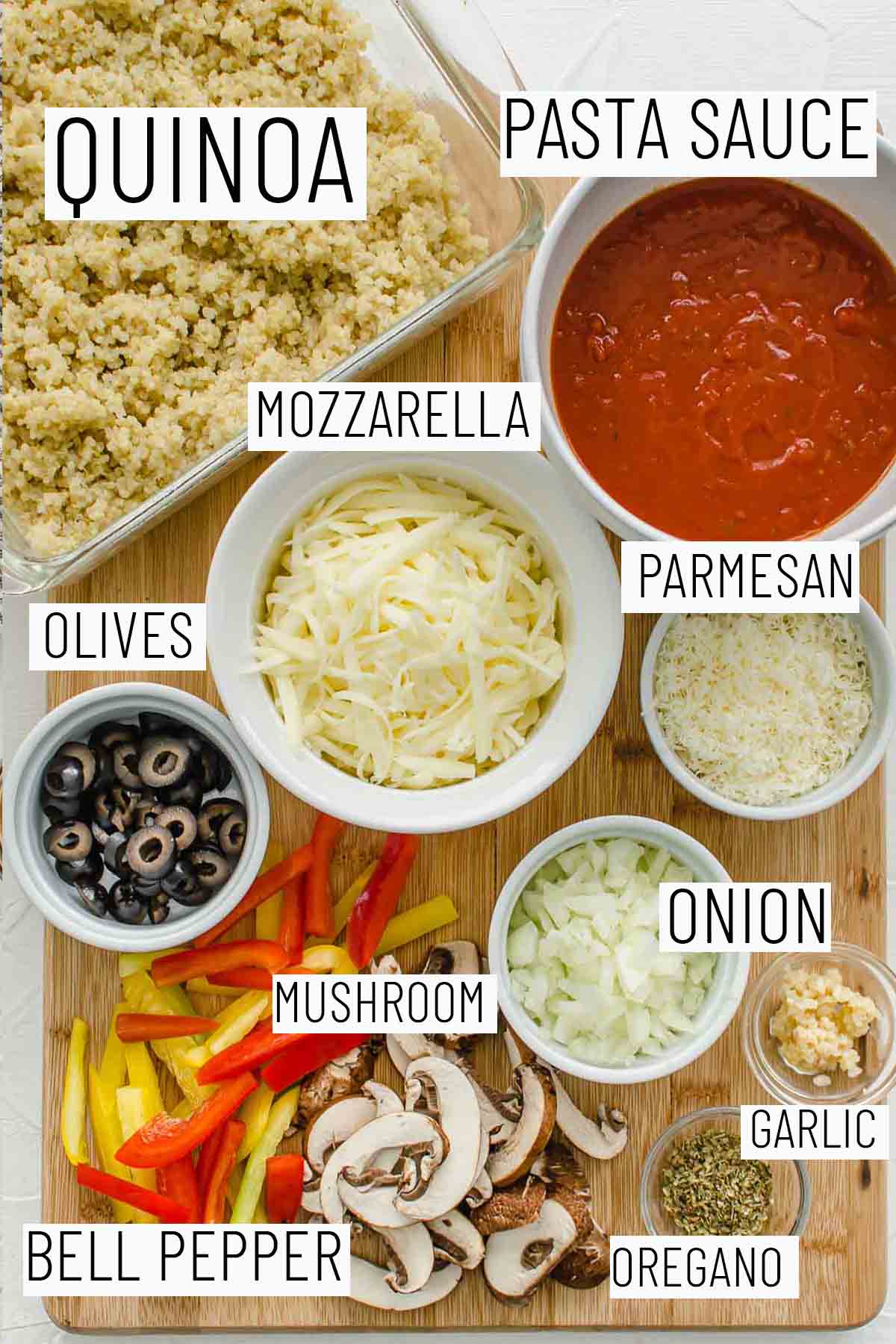 Flat lay image of portioned recipe ingredients including parmesan, mozzarella, olives, onion, garlic, oregano, bell pepper, quinoa, and pasta sauce. 