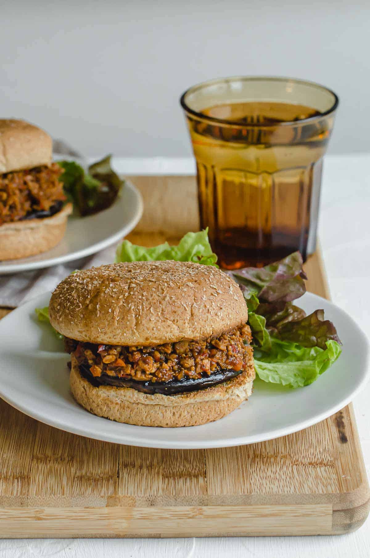 Close up of vegan sloppy joe on a white plate with a glass of water in the background.