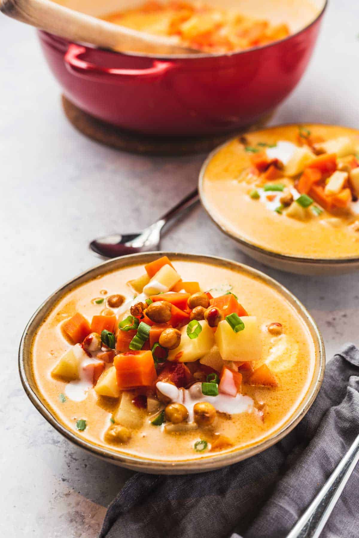 Close up image of two portions of gochujang soup in a bowl and garnished with chickpeas and scallions. 