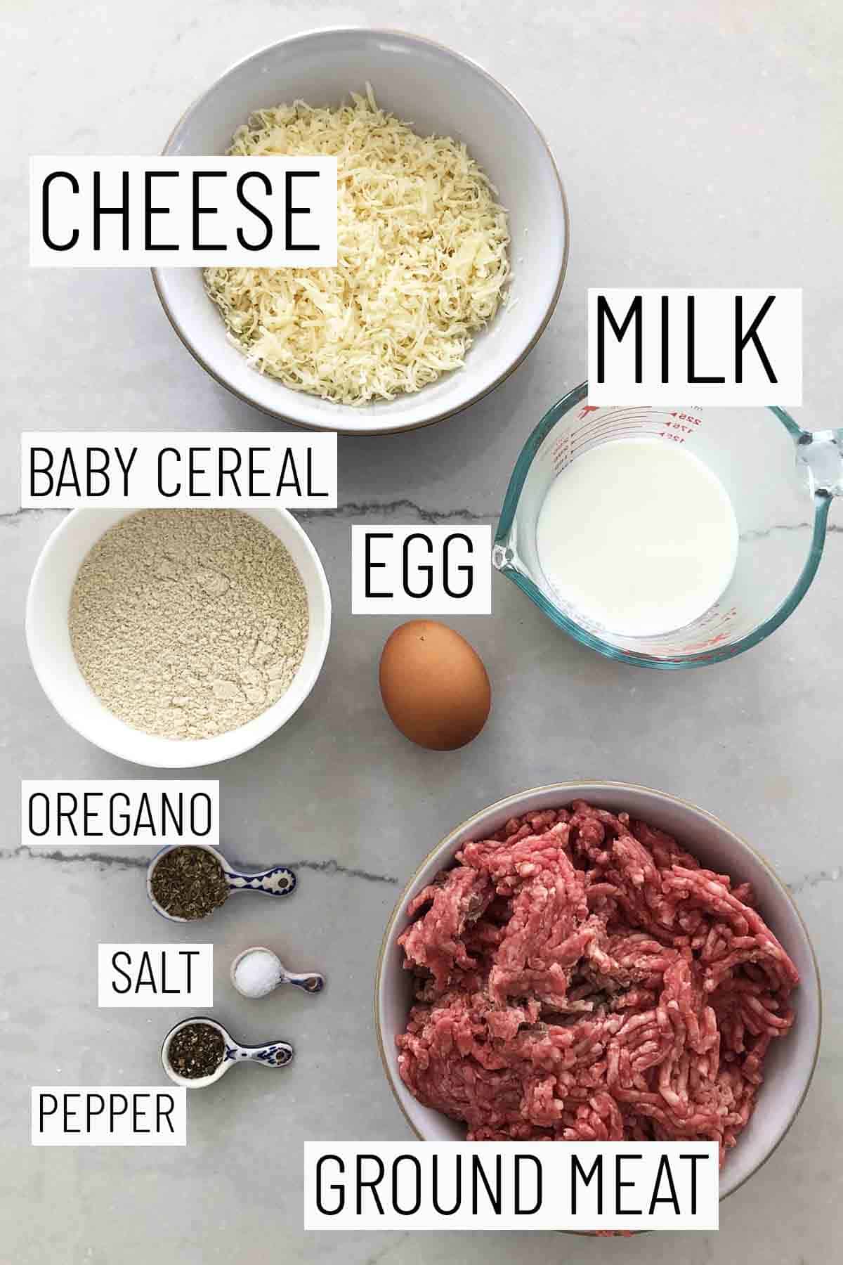 Flat lay image of portioned recipe ingredients including ground meat, pepper, salt, oregano, baby cereal, egg, milk, and cheese. 