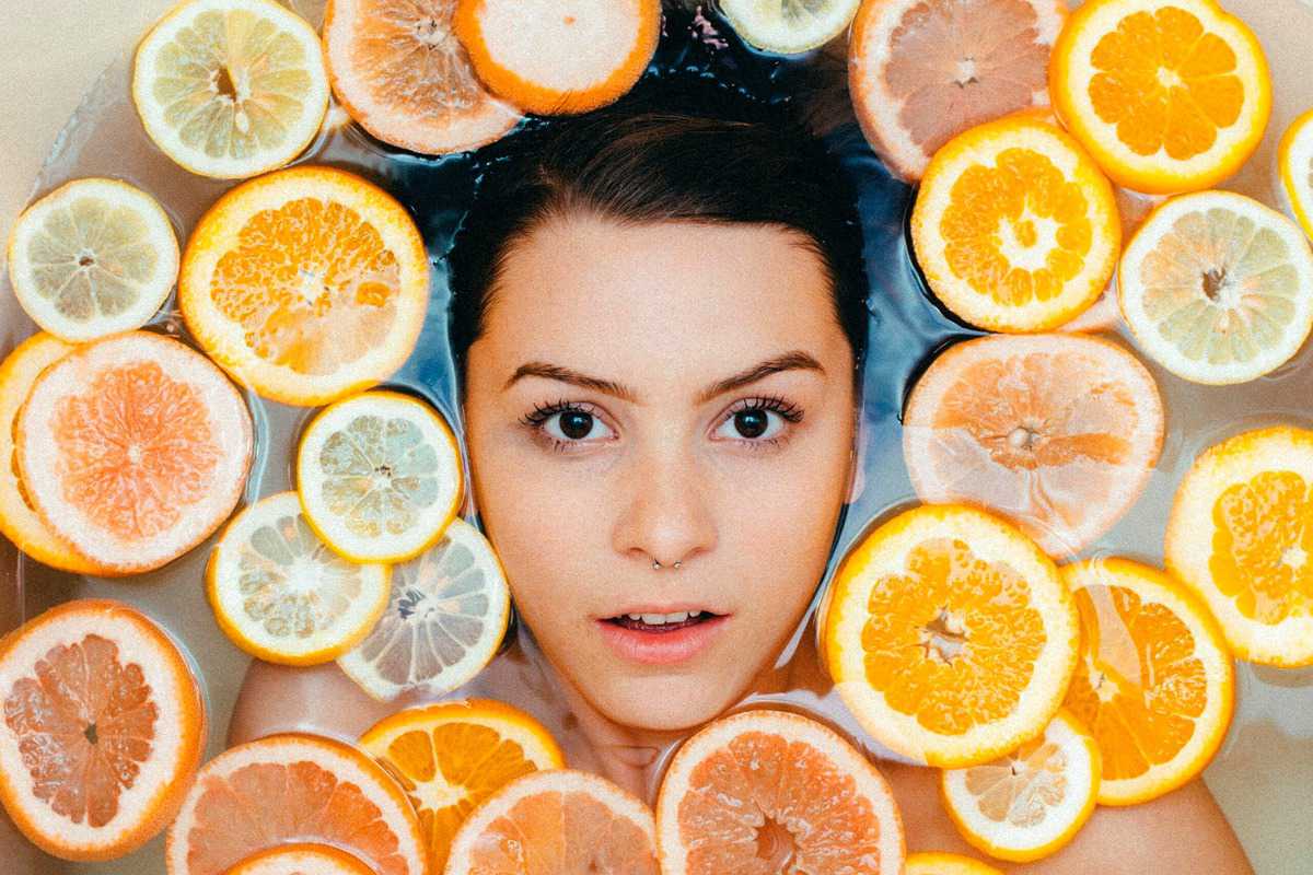 Woman in a bath tub surrounded by orange slices. 