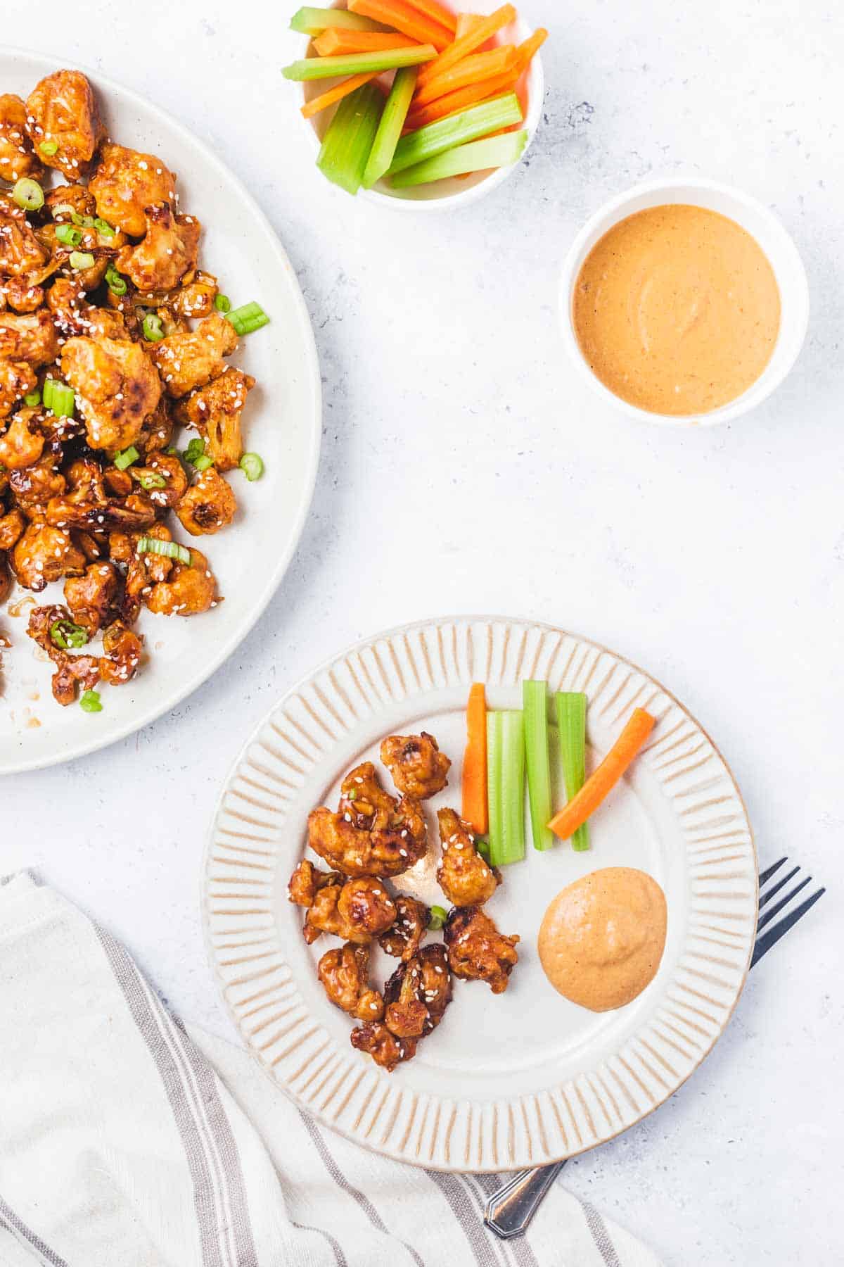 Overhead view of a plate with a handful of vegan cauliflower wings, dip, and vegetables.