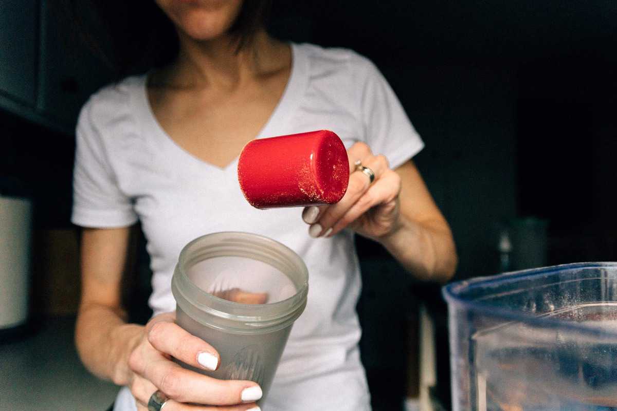 A women scooping supplement into a portable bottle. 